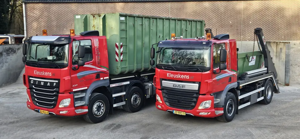 Rode portaalarmwagen van Kleuskens met een groene portaalarmcontainer tussen de armen